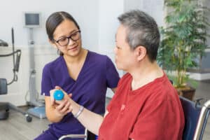A physical therapist and a resident at the Canyon Springs rehab gym lifting a dumbbell
